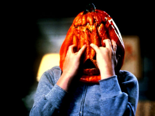 A child claws at the pumpkin mask he's wearing in a scene from Halloween III: Season of the Witch